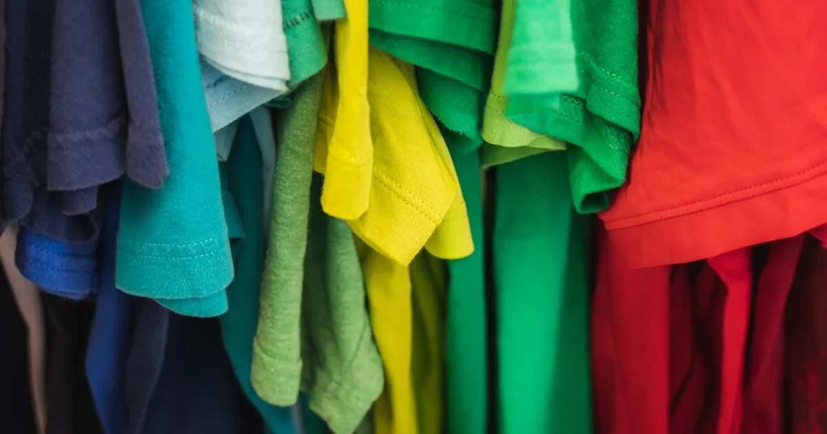 Camisetas penduradas em várias cores em arara de loja