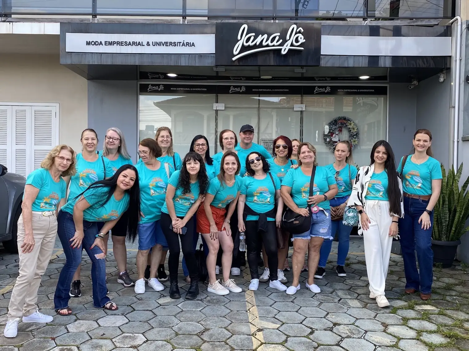 Grupo de clientes vestindo camisetas personalizadas em frente à loja Jana Jô